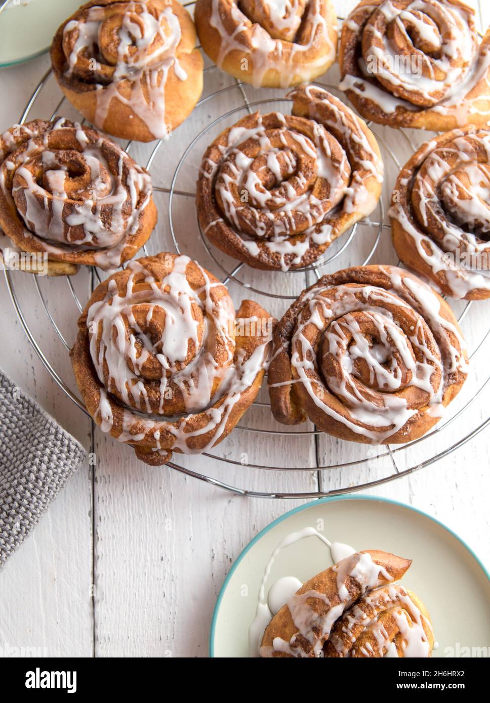 Dolci alla cannella appena sfornati fatti in casa con glassa di zucchero serviti su una griglia di raffreddamento. Vista dall'alto, immagine verticale Foto Stock