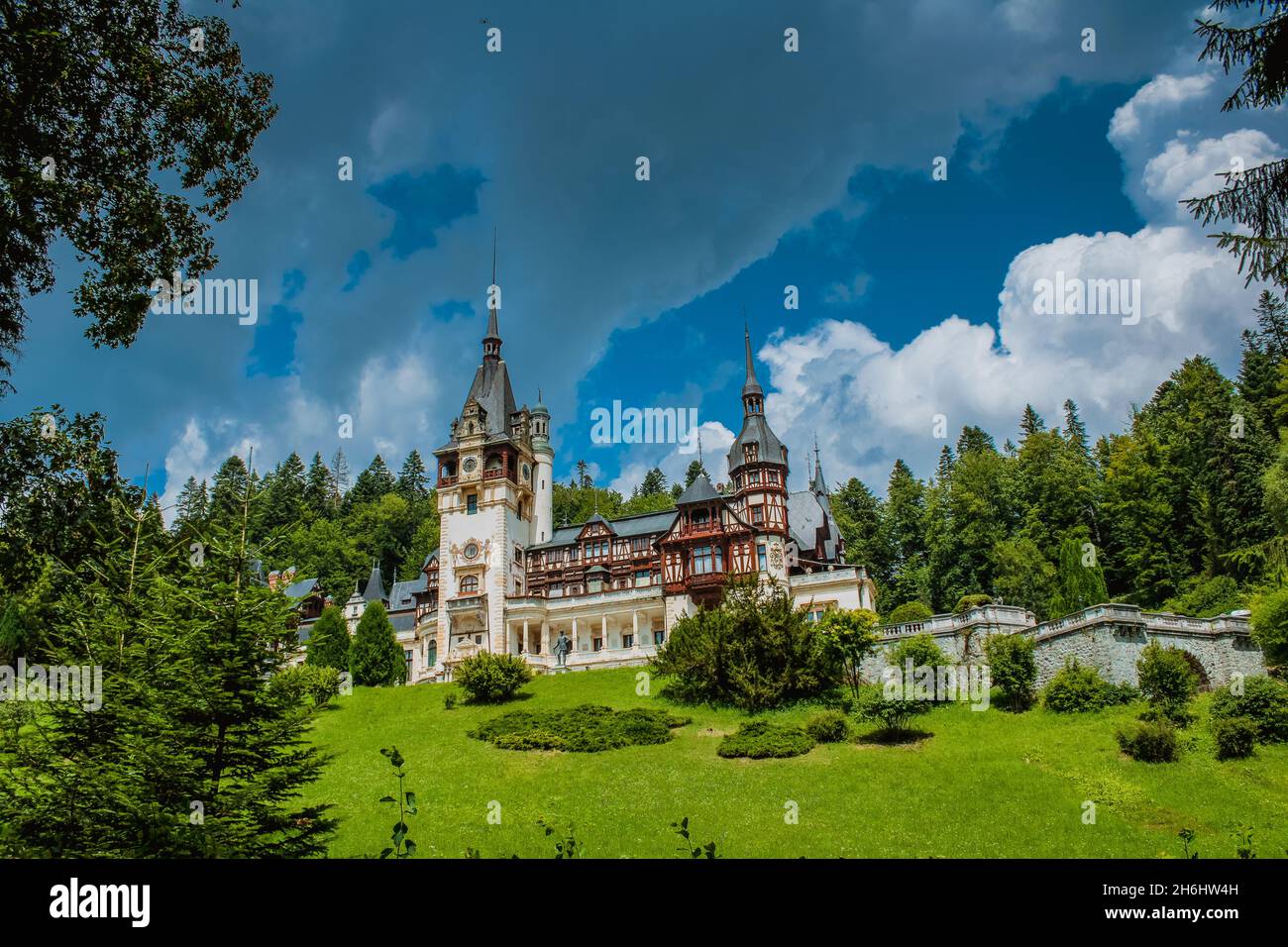 palazzo Peles dal fronte in Romania, castello in montagne con cielo su sfondo circondato da alberi Foto Stock