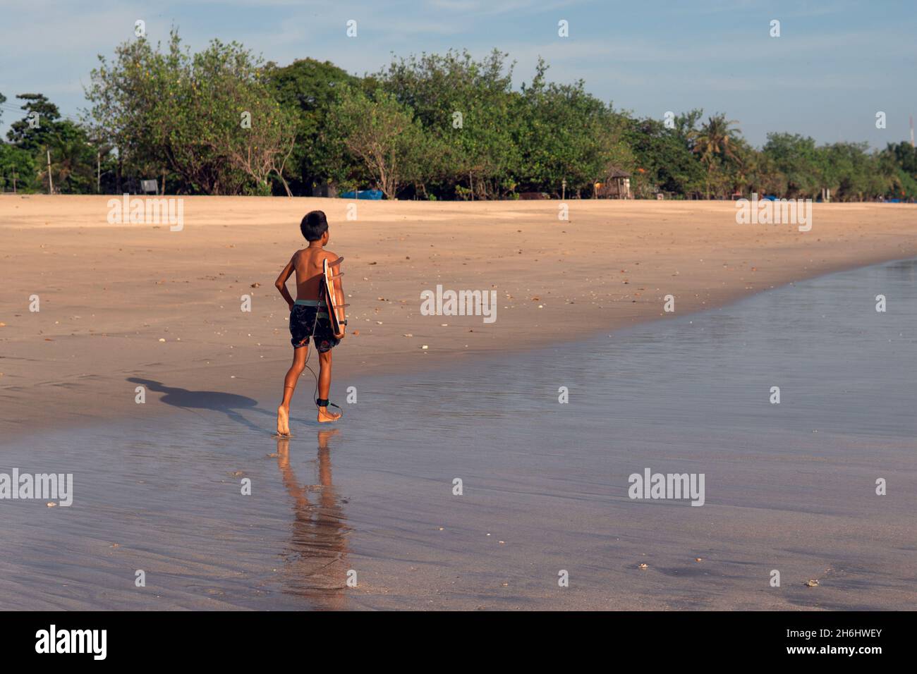 surfista in pantaloncini neri camminando lungo la spiaggia. bali Foto Stock