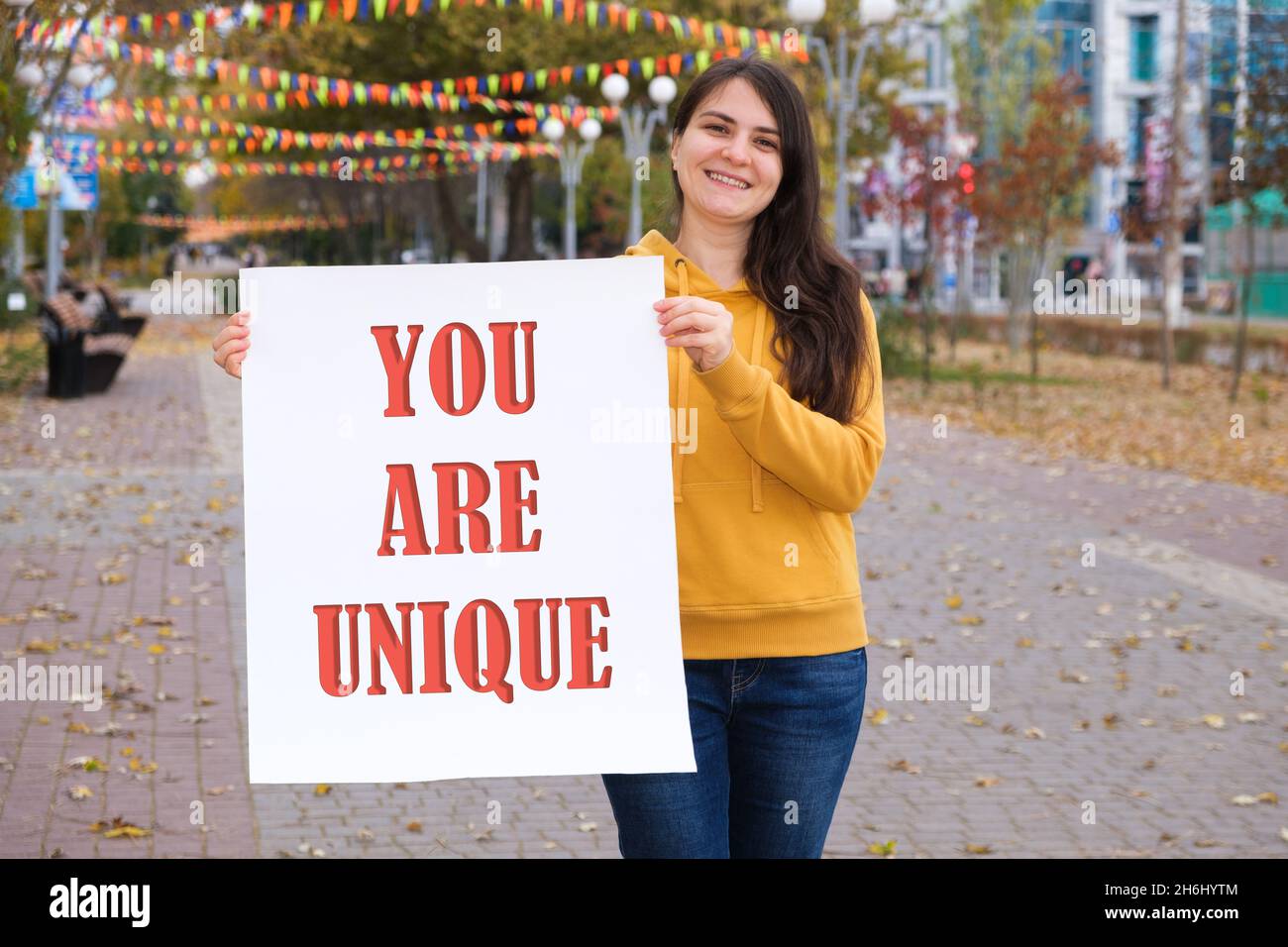 Una donna brunetta senza trucco tiene un poster con il testo che si è unico Foto Stock