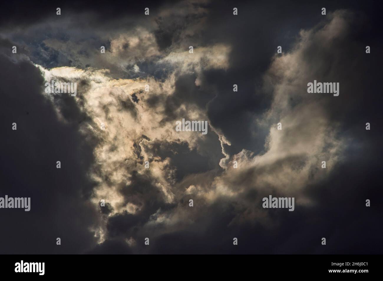 Cielo scuro e chiaro d'estate. Nuvole basse e irregolari parzialmente illuminate dal sole, prima del tramonto, guardando a ovest dal Monte Tamborine, Australia. Sfondo. Foto Stock