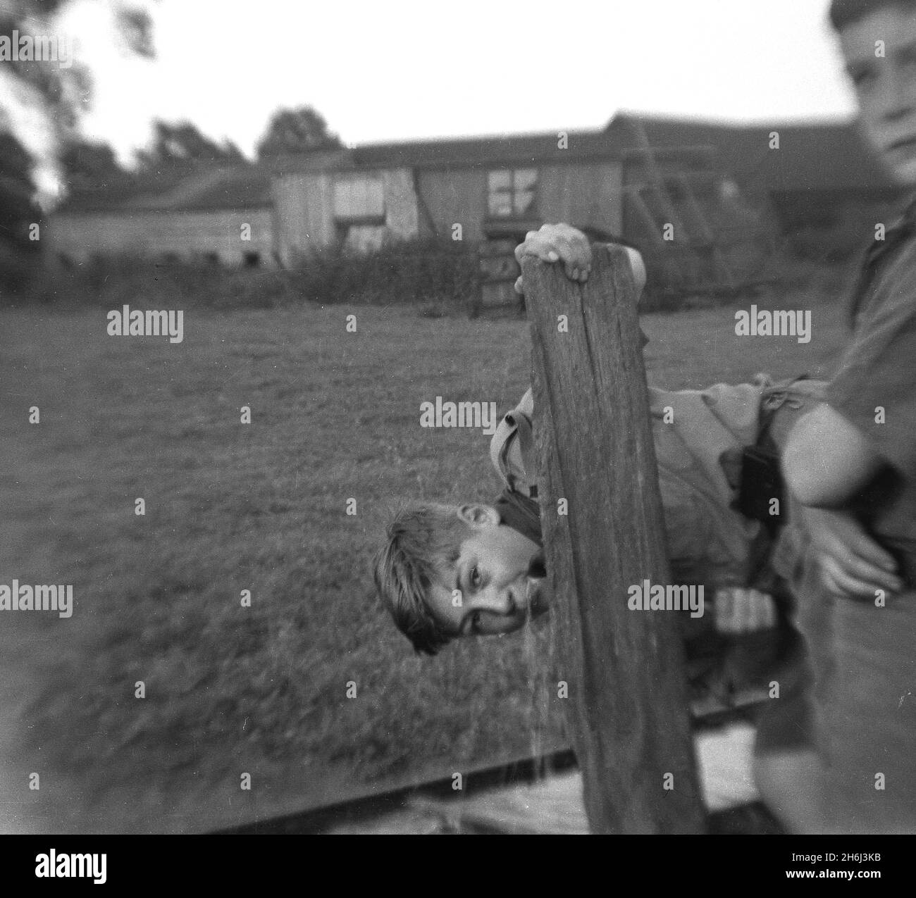 1937, storico, all'esterno, accanto ad un campo rurale, un cub scout che ha una bevanda di da un rubinetto d'acqua su un palo di legno, Inghilterra, Regno Unito. Scouting iniziò nel 1908, dopo che il British Army Officer, Robert Baden-Powell tenne un campo sperimentale sull'isola di Brownsea, Poole Harbour, l'estate precedente. Circa 20 ragazzi hanno partecipato e sono stati insegnati una serie di abilità all'aperto, tra cui monitoraggio, vigili del fuoco, realizzazione di rifugi da rami, annodamento, cucina, salute e igiene, salvavita e pronto soccorso. Il famoso libro di Baden-Powell, 'Scouting for Boys', fu pubblicato per la prima volta nel 1908. Foto Stock