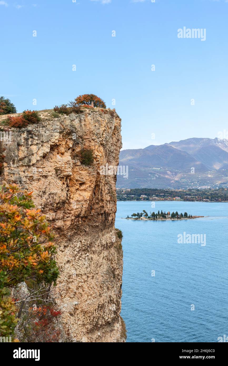 Scogliera rocciosa del Lago di Garda e vista sulla piccola isola di Rabbit (periodo autunnale) Foto Stock