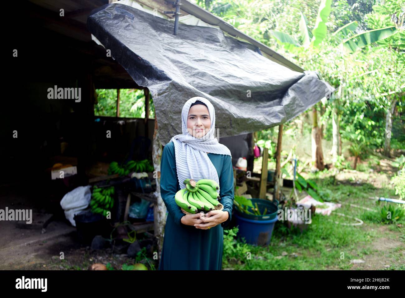Donna musulmana in piedi hijab e tenendo la banana cruda in casa Foto Stock