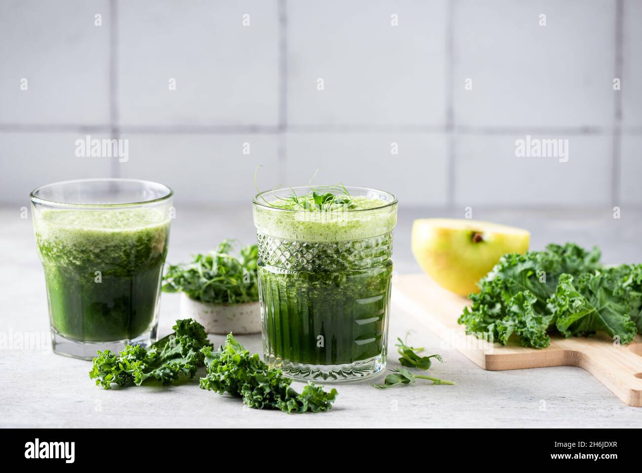 Frullato disintossicante vegano verde in vetro al tavolo da cucina. Perdita di peso, concetto di succo di disintossicazione Foto Stock