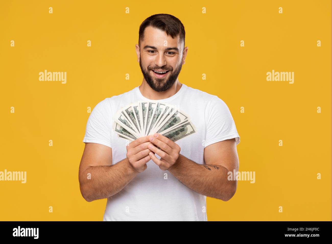 Eccitato felice uomo europeo di mezza età si rallegra per la vittoria e guarda un sacco di soldi nelle mani Foto Stock