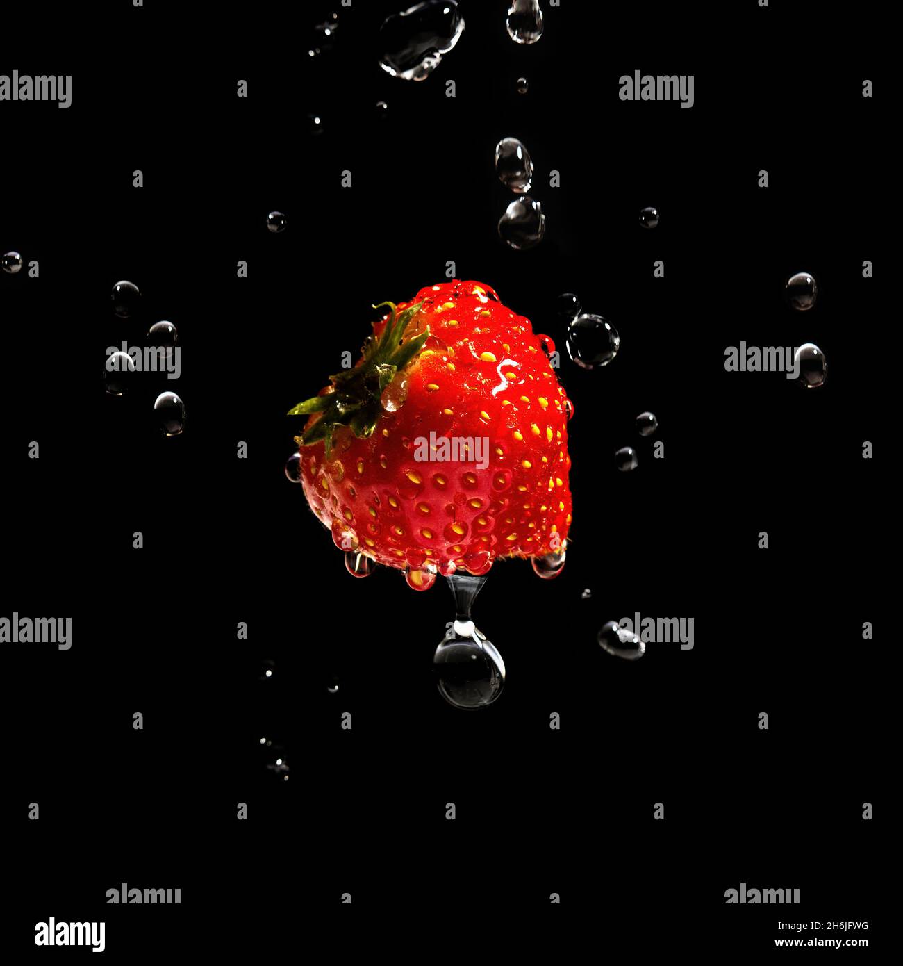 Fragola luminosa circondata da spruzzi d'acqua e gocce vola attraverso l'aria Foto Stock