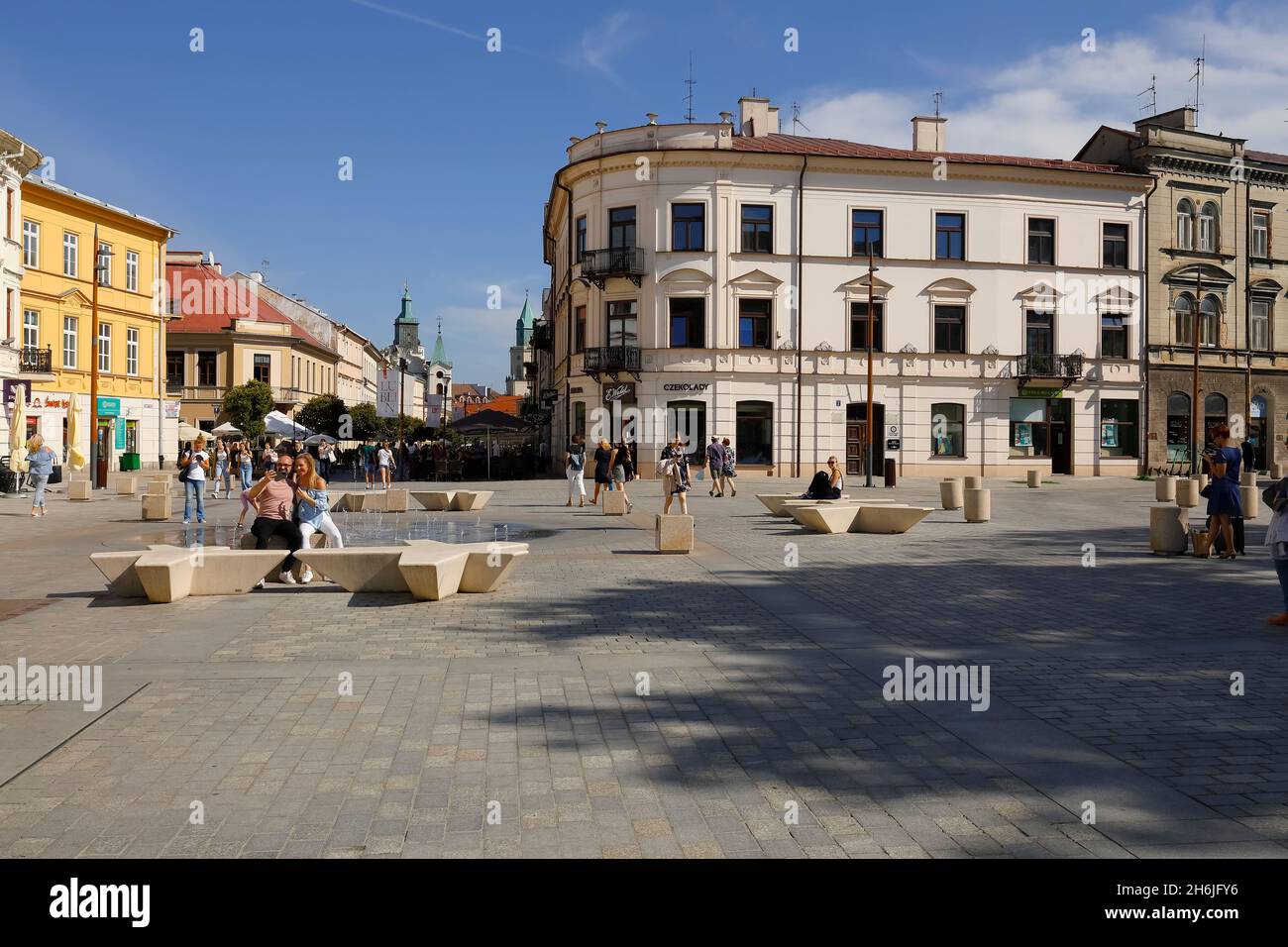 Lublino, Polonia - 10 settembre 2021: Una grande piazza circondata da case antiche. C'è una piccola fontana nella piazza e ci sono peop Foto Stock