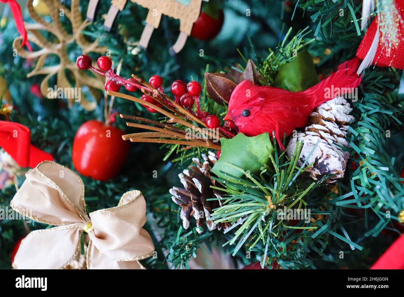 Primo piano dell'albero di Natale con decorazione natalizia: Uccello rosso, nastri, mele rosse, pinecones... alla luce del giorno. Foto Stock