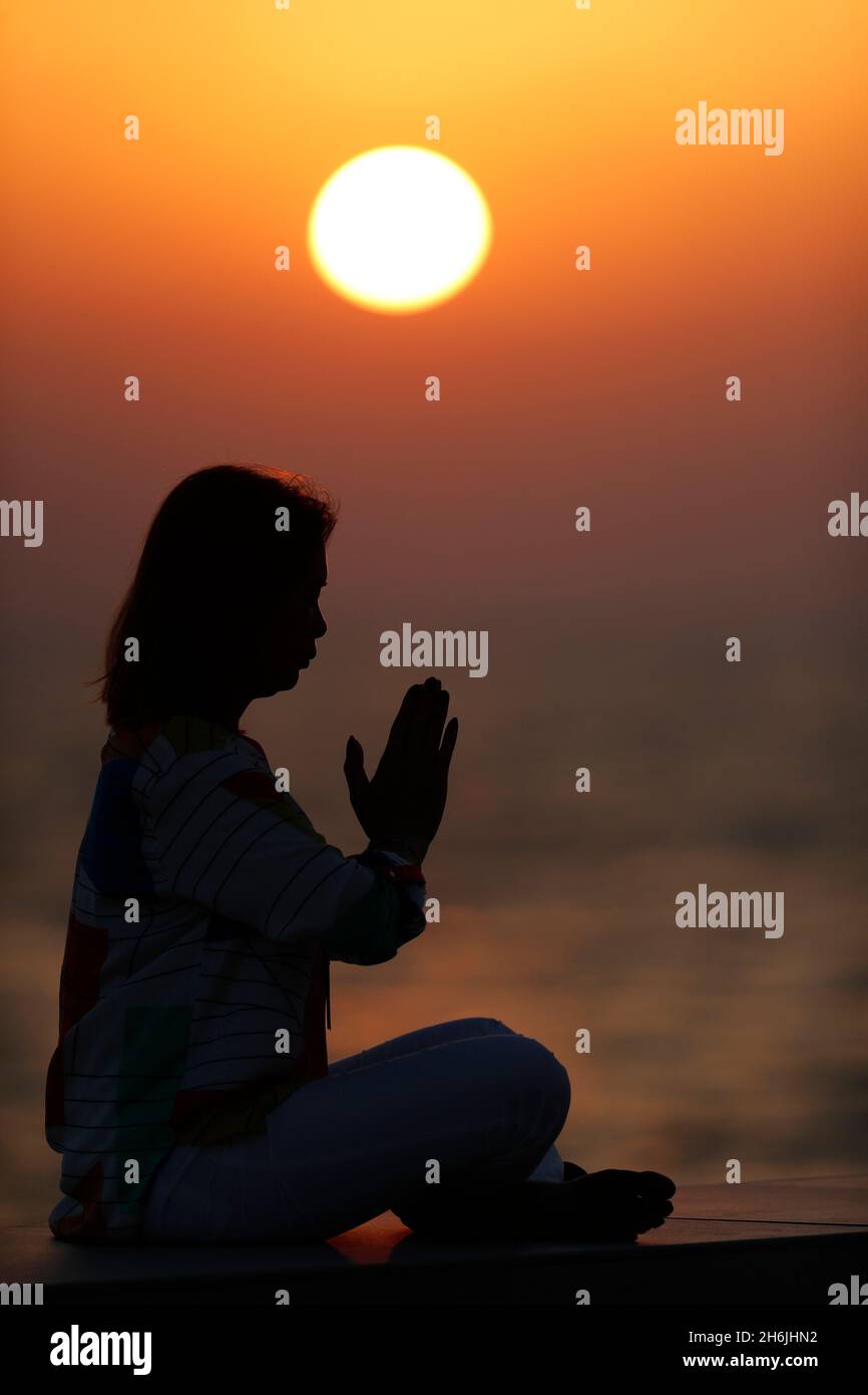 Donna che pratica yoga posa e meditazione al tramonto come concetto di silenzio e relax, Emirati Arabi Uniti, Medio Oriente Foto Stock