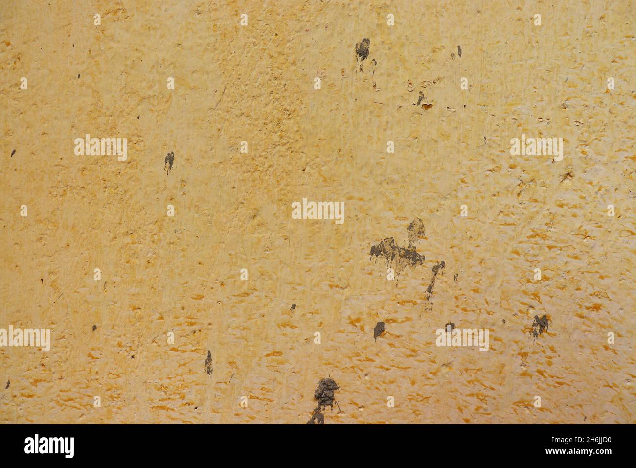 Vecchio, giallo parete testurizzata macchiata con macchie di cemento, per l'uso di fondo. Foto Stock