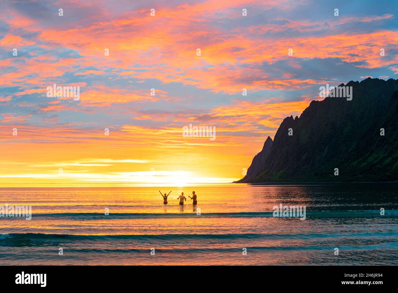 Donna allegra con amici che si divertono in mare durante il sole di mezzanotte, Ersfjord, Senja, contea di Troms, Norvegia, Scandinavia, Europa Foto Stock