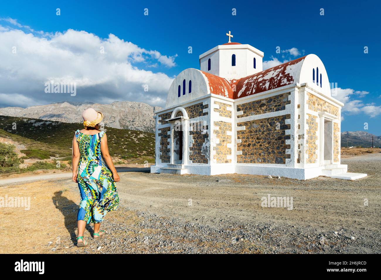Vista posteriore della donna in abito e cappello di paglia che cammina verso la chiesa greco-ortodossa di Agia Fotini, Pachia Ammos, Creta, Isole greche, Grecia, Europa Foto Stock