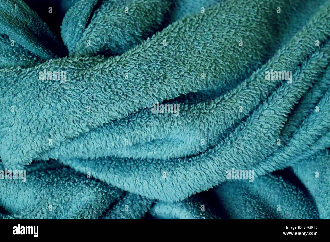 Primo piano di coperta blu, verde, morbida, calda, confortevole, illuminata dalla luce del mattino presto, subito dopo il risveglio. Foto Stock