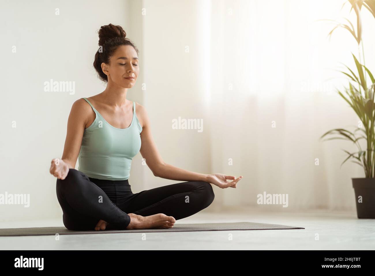 Meditazione del mattino. Bella calma Donna meditating a casa in posizione Lotus Foto Stock
