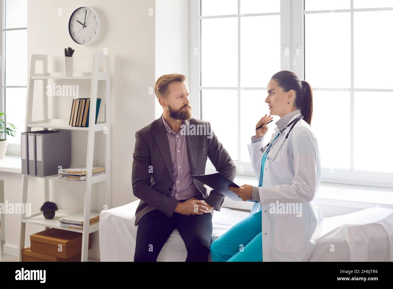 Il paziente maschio imbarazzato discute il trattamento con il suo medico durante la riunione all'ufficio dell'ospedale. Foto Stock