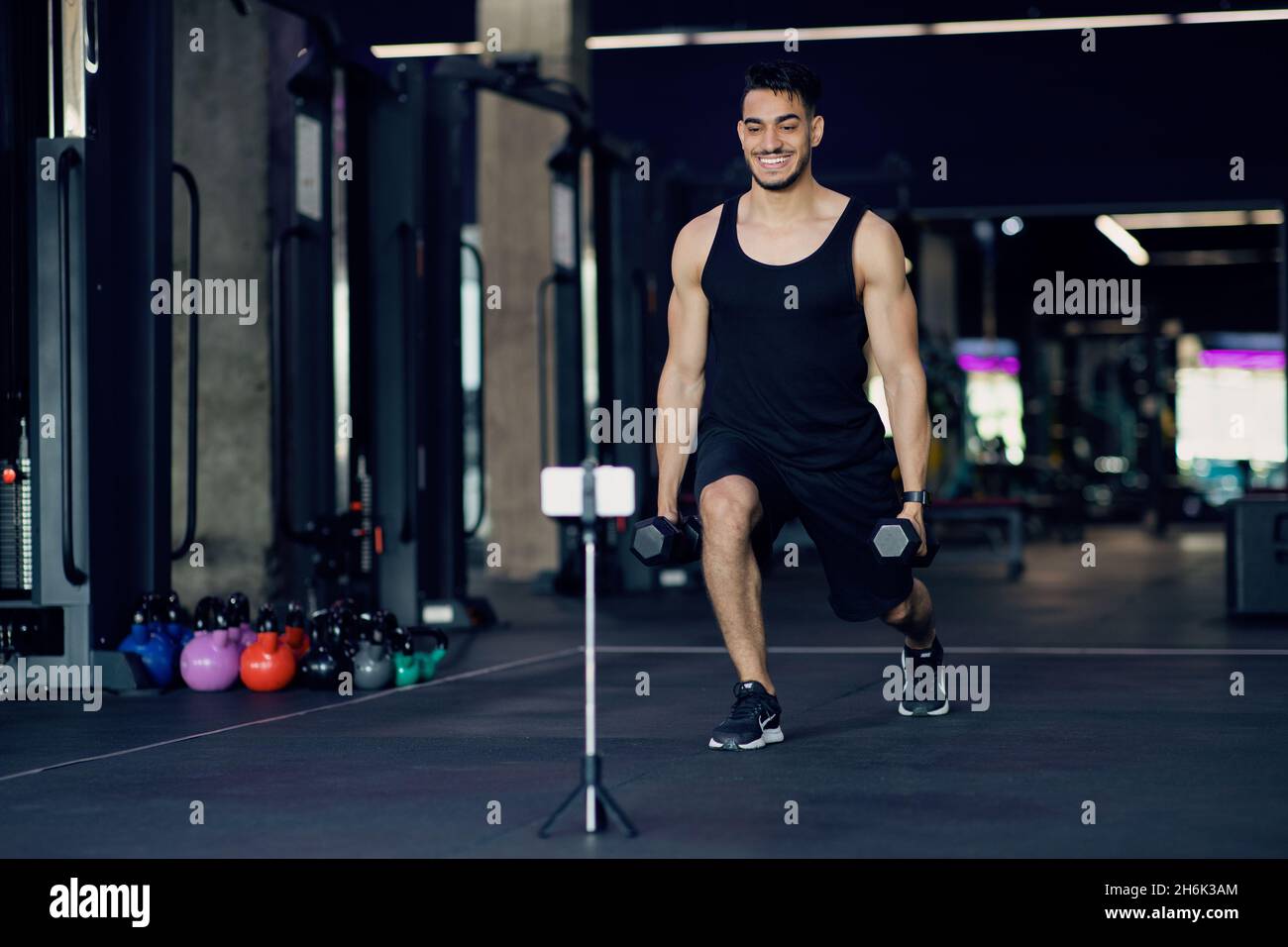 Allenatore di Fitness maschio Arabo che cattura i video di formazione in palestra per il suo blog Foto Stock