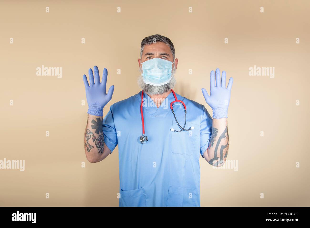 Ritratto del medico gesturante mentre in piedi contro parete background.Health lavoratori, covid-19, coronavirus e virus prevenzione concetto. Foto Stock