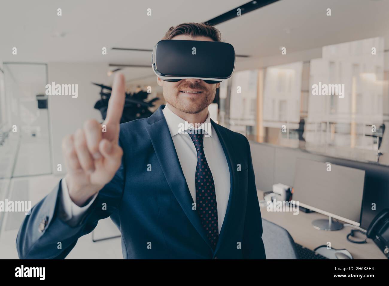 CEO MAN è in ufficio con visore VR e interagisce con l'interfaccia virtuale dell'applicazione Foto Stock