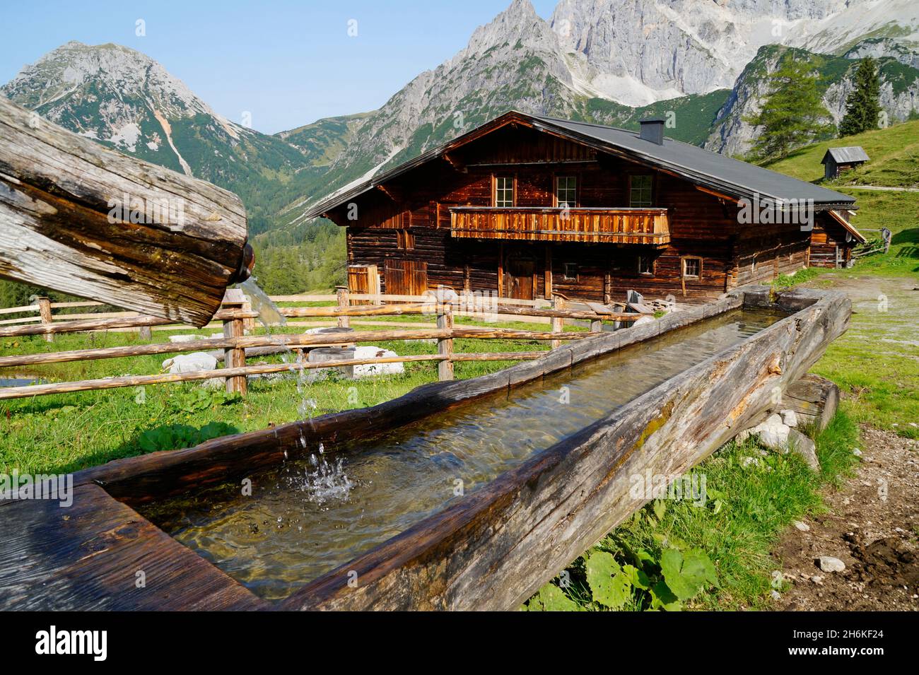 Una casa rustica in legno e un canale d'acqua a Neustatt Alm nelle Alpi austriache nella regione di Dachstein (Stiria in Austria) Foto Stock