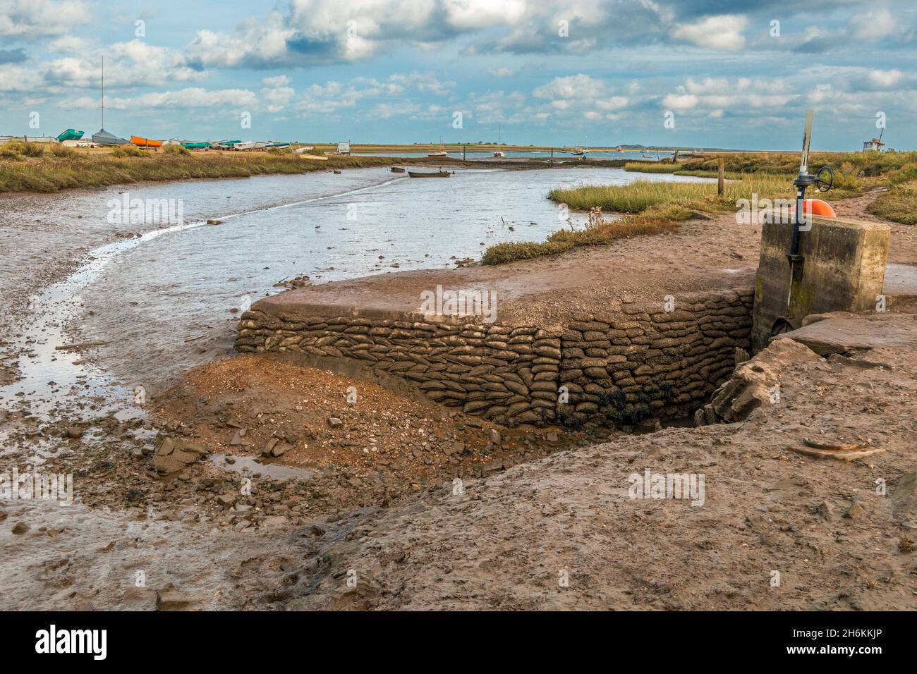 Sacchi di sabbia che proteggono scarico a bassa marea a Brancaster Staithe Harbour Nord Norfolk Inghilterra Foto Stock