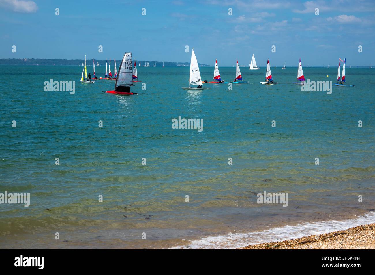 Vela dingie corse su mare calmo sul Solent a Stokes Bay Gosport Hampshire Inghilterra Foto Stock