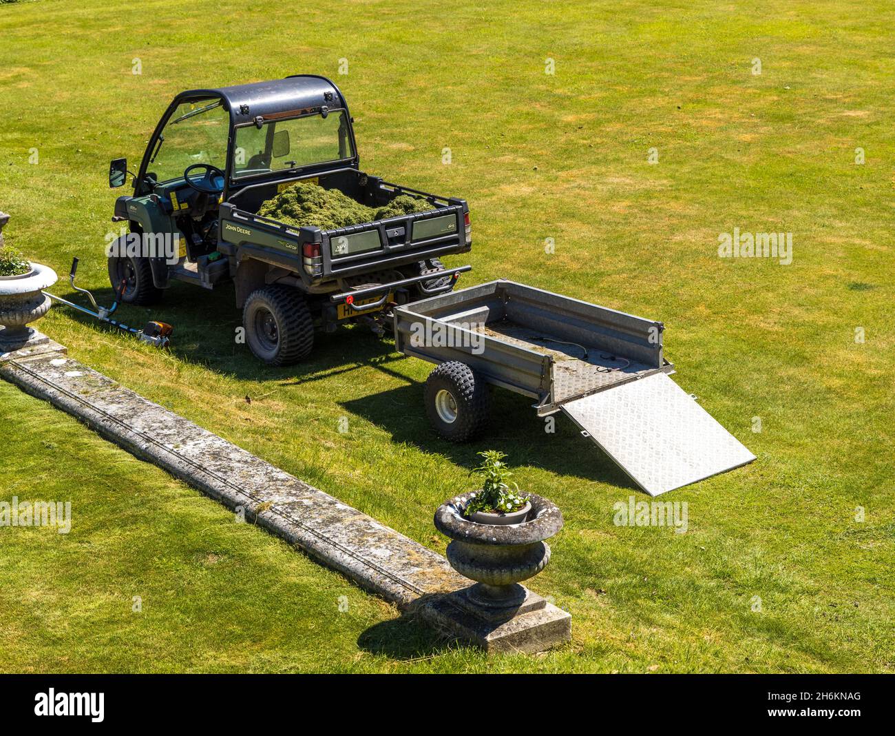Attrezzatura da giardinaggio commerciale un John Deere Gator XUV 4x4 con rimorchio per la raccolta di detriti di erba Foto Stock