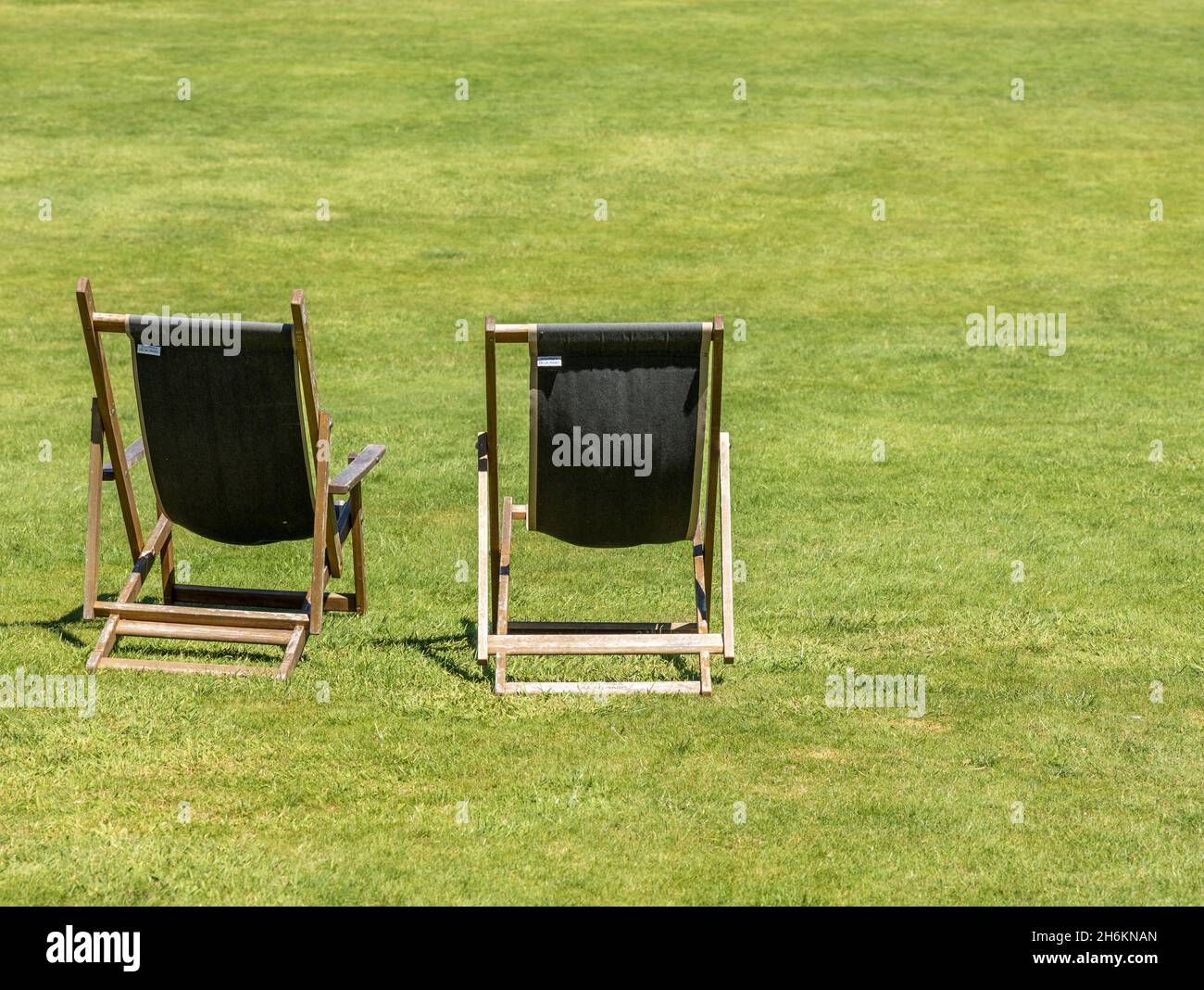 Due sedie a sdraio tradizionali aspettano i visitatori sul prato verde Dorset Inghilterra Foto Stock