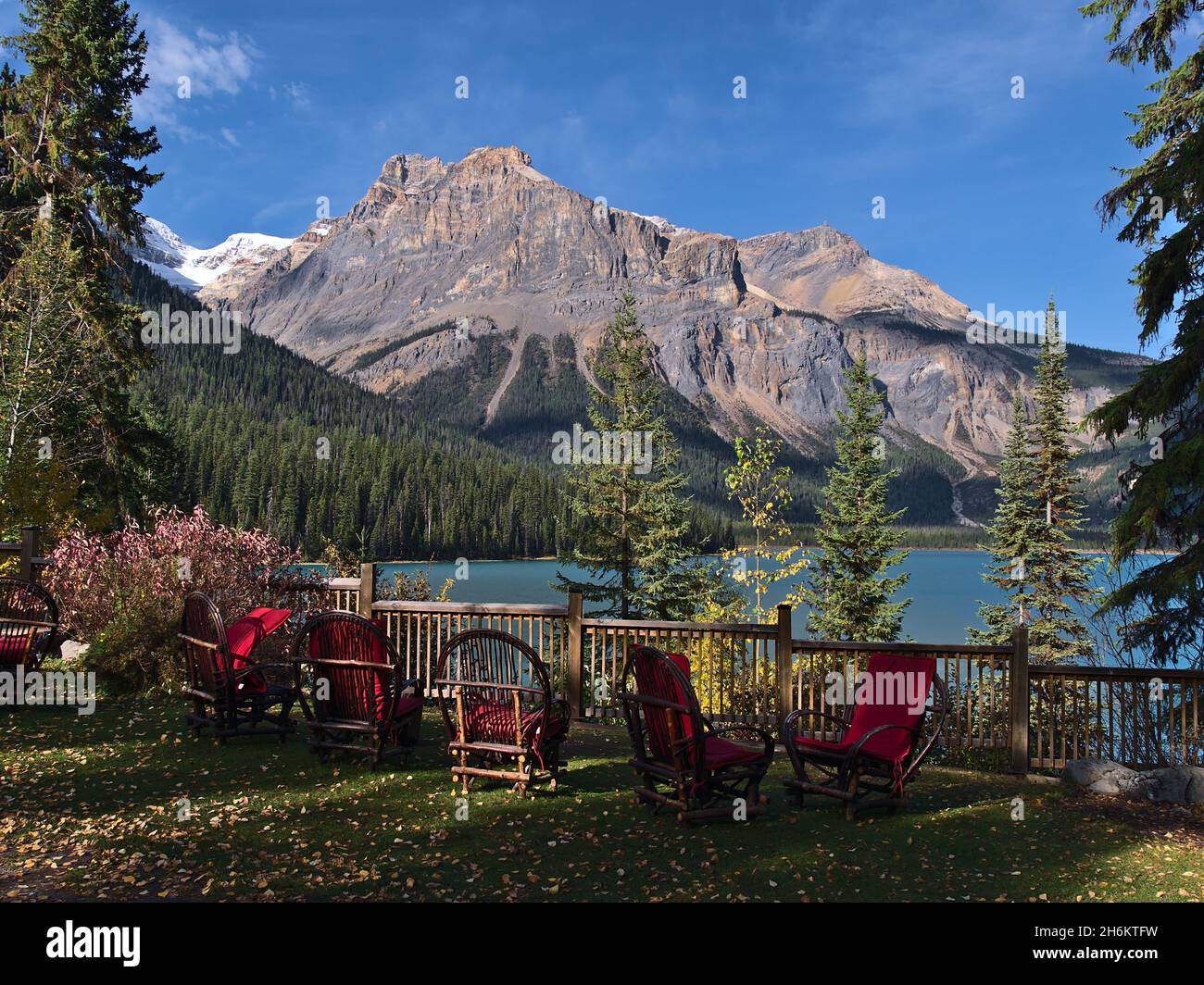 Splendida vista sul famoso lago Emerald nel parco nazionale di Yoho, British Columbia, Canada, nelle Montagne Rocciose con sedie di legno e cuscini rossi. Foto Stock