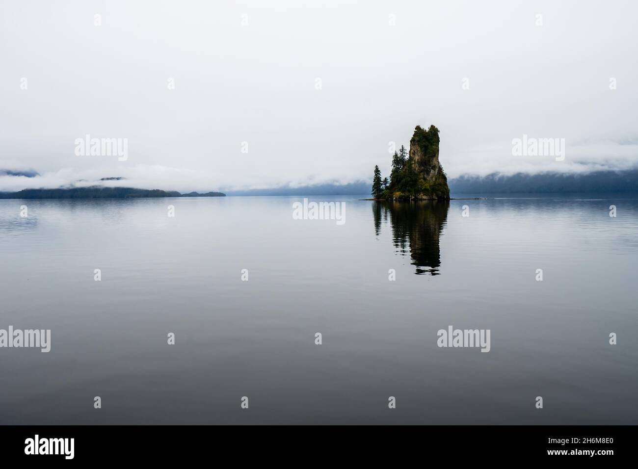 Roccia isolata che sporge dalle acque ferme Foto Stock