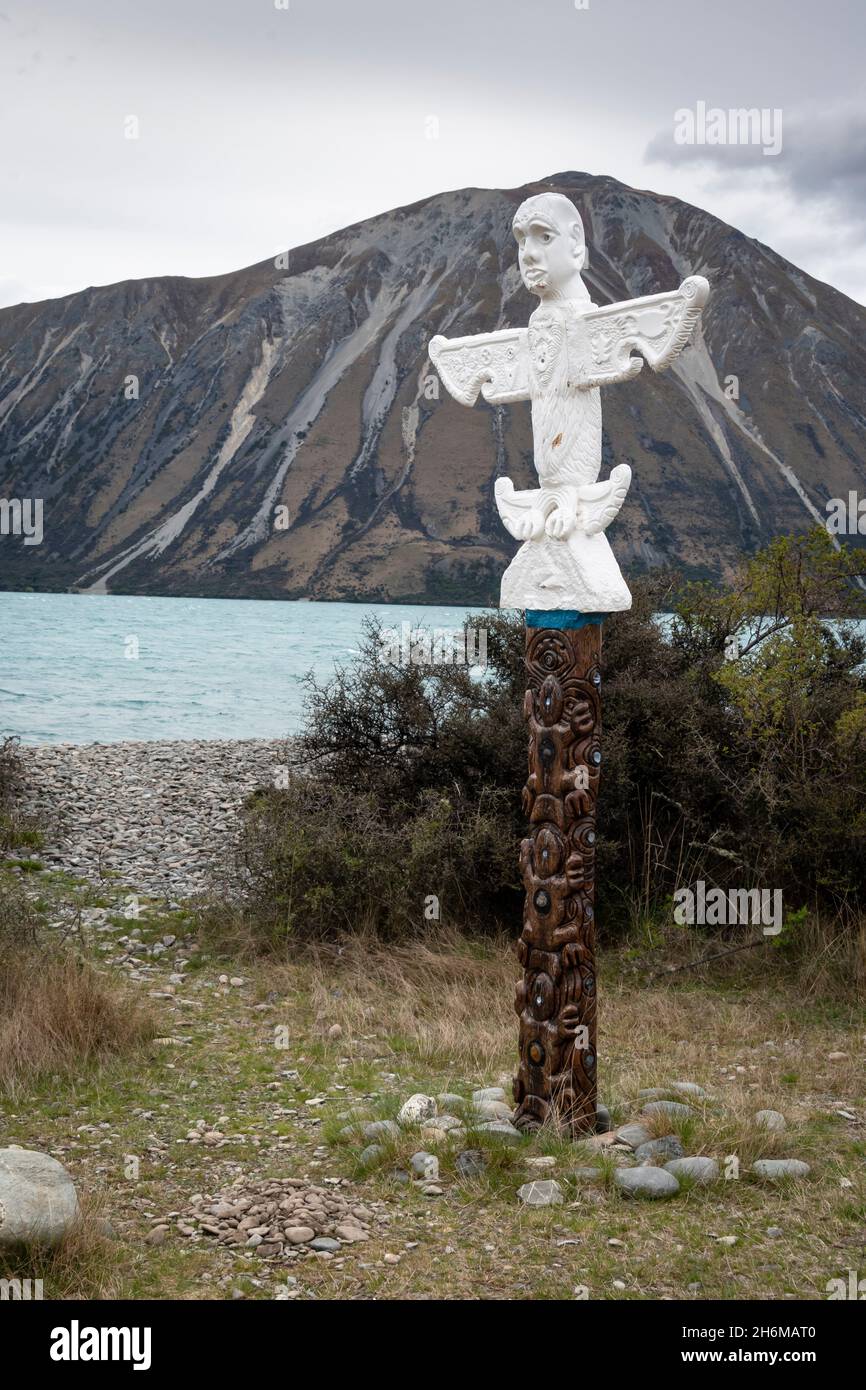 Maori Pou (statua) per commemorare gli insegnamenti di te Maiharoa, Lago Ohau, MacKenzie, Canterbury Sud, Isola del Sud, Nuova Zelanda. Ben Ohau in lontanamento Foto Stock