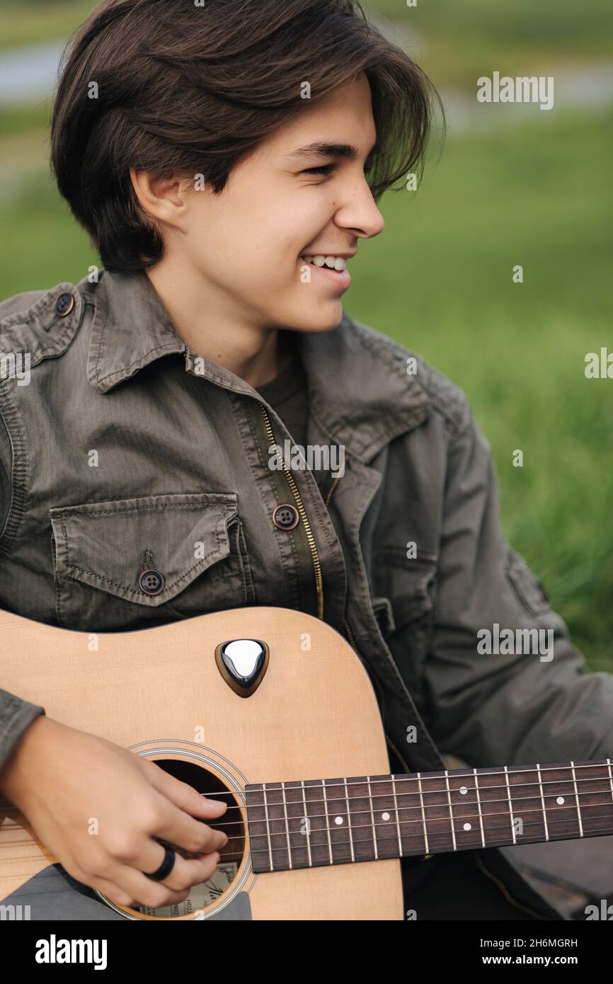 Ritratto di bel ragazzo teenage suonando la chitarra all'aperto. Ragazzo  con chitarra classica. Maschio da solo facendo musica Foto stock - Alamy