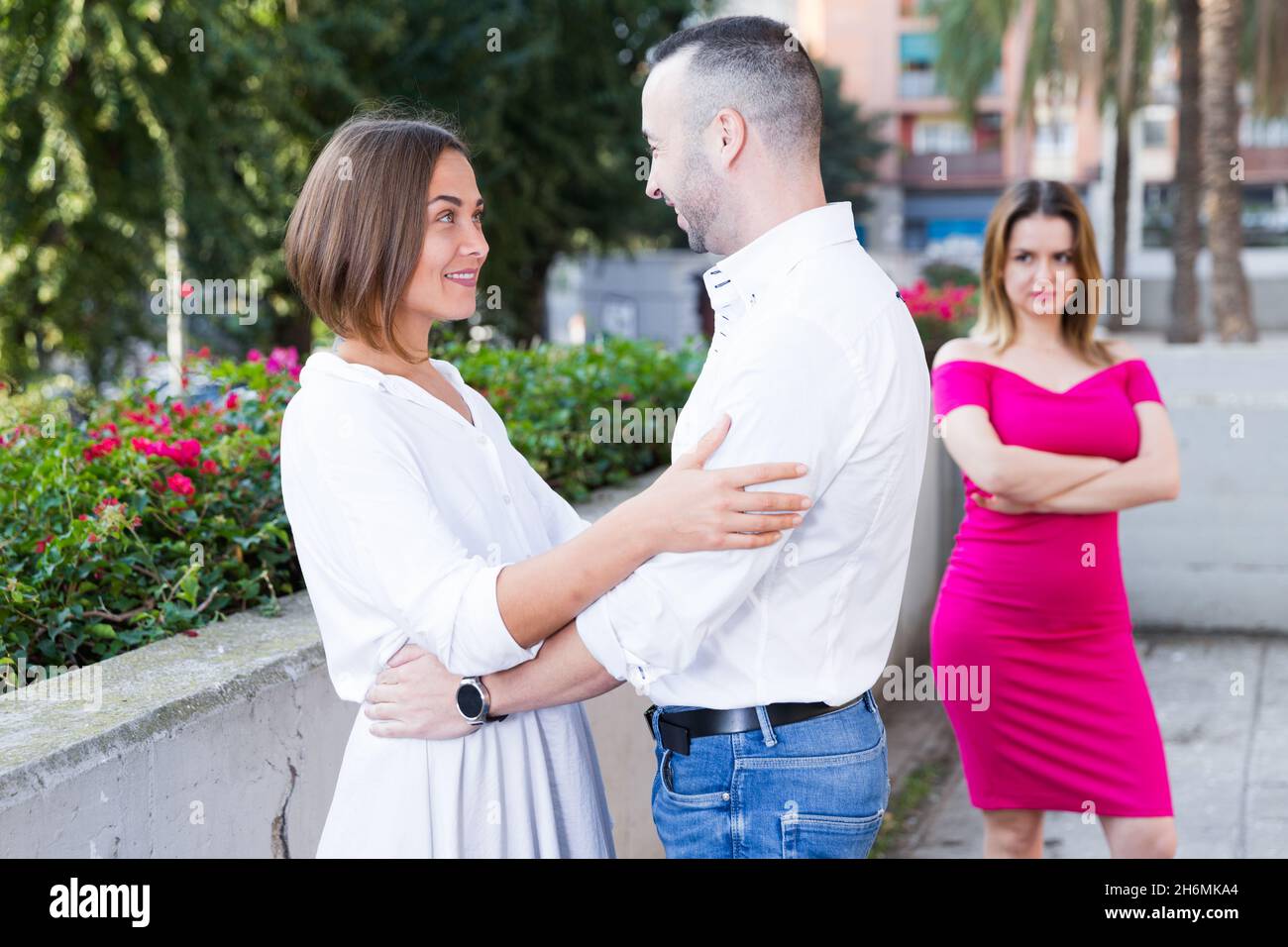La giovane donna flirting con il ragazzo quando la sua ragazza li sta invidiando Foto Stock