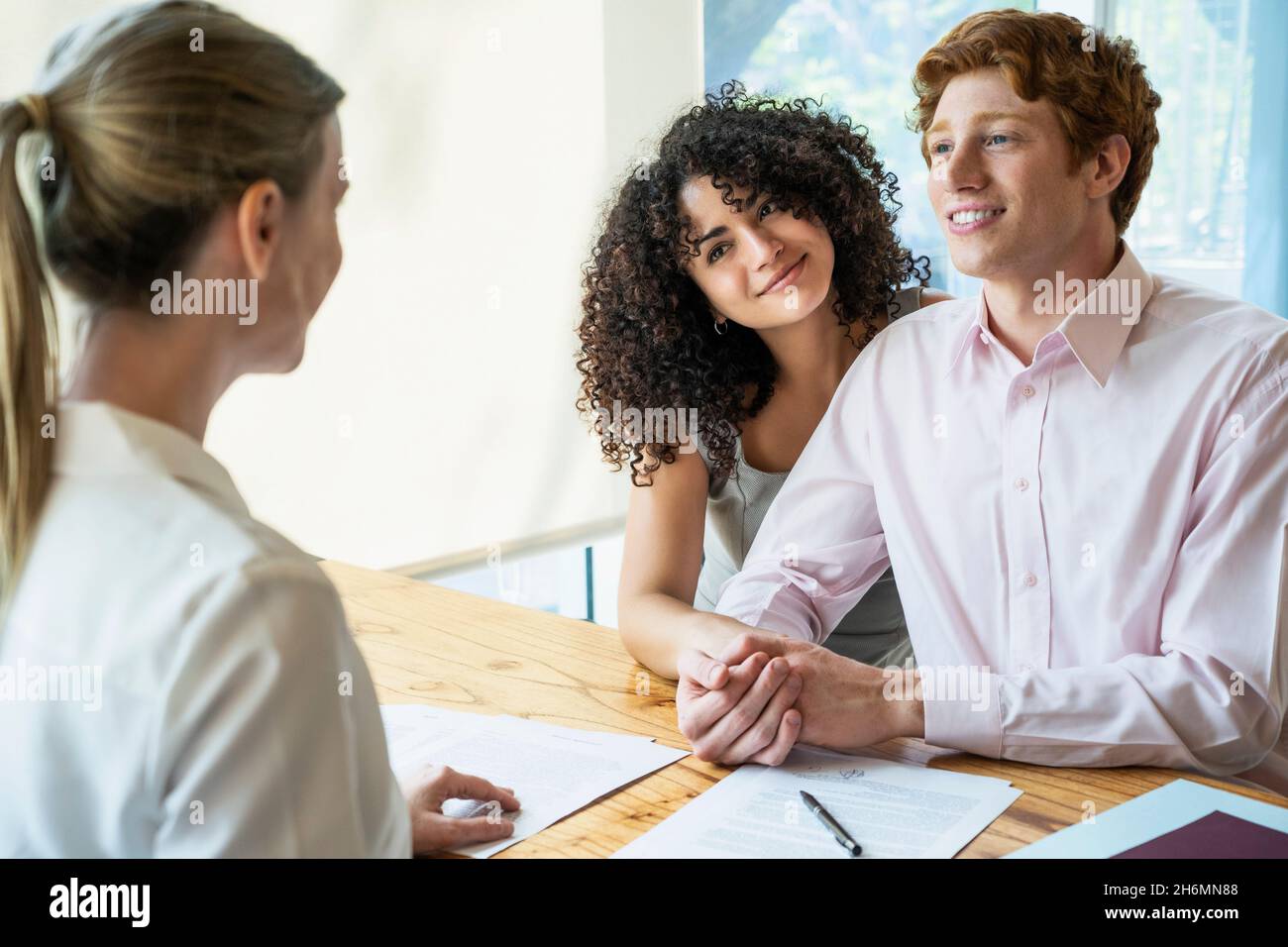 Giovane coppia firma contratto in ufficio Foto Stock