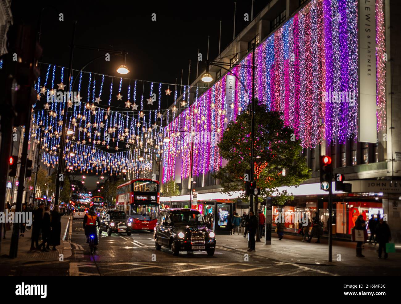 John Lewis grande magazzino a Oxford Street, Londra, Regno Unito, illuminato di notte per Natale come Londra taxi e autobus passano vicino. 15 novembre 2021. Foto Stock