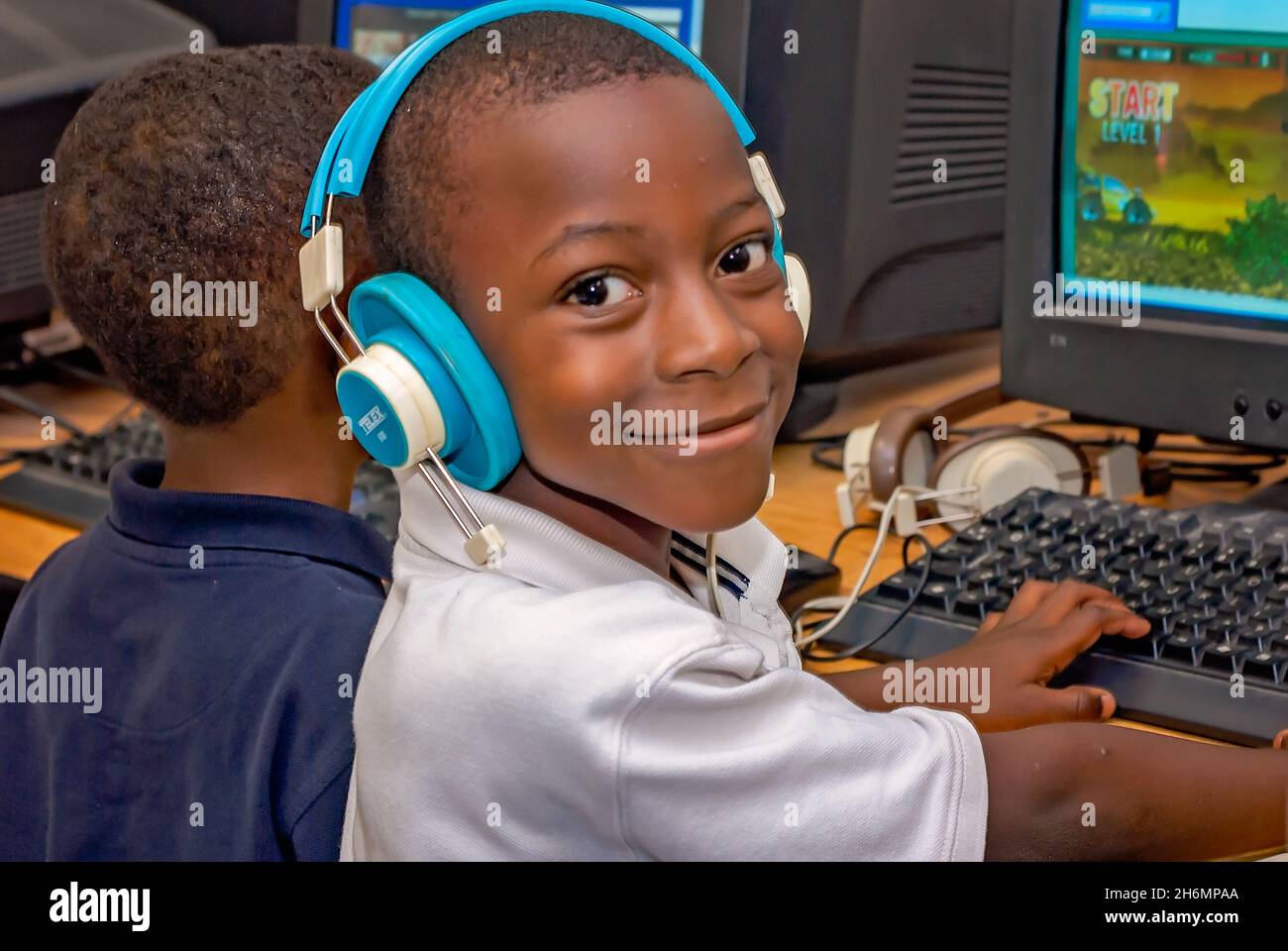Uno studente afroamericano indossa le cuffie mentre gioca un gioco per computer l'ultimo giorno di scuola, il 13 giugno 2011, a Columbus, Mississippi. Foto Stock