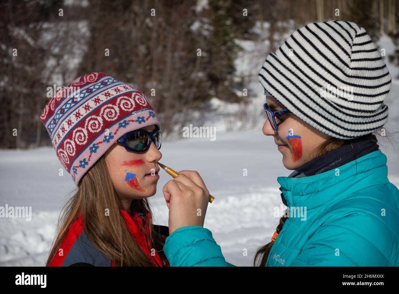 Due giovani ragazze, una con capelli lunghi, indossando cornici e caldi abiti invernali che dipingono i loro volti fuori nella neve al Chama Chile Ski Classic. Foto Stock