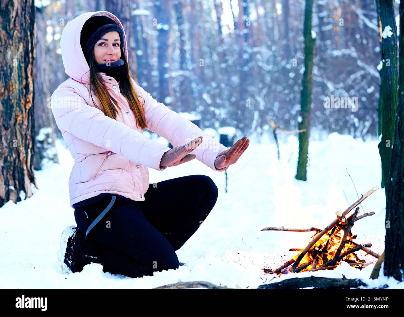 Giovane donna in un pic-nic invernale nella foresta riscaldamento vicino al fuoco Foto Stock