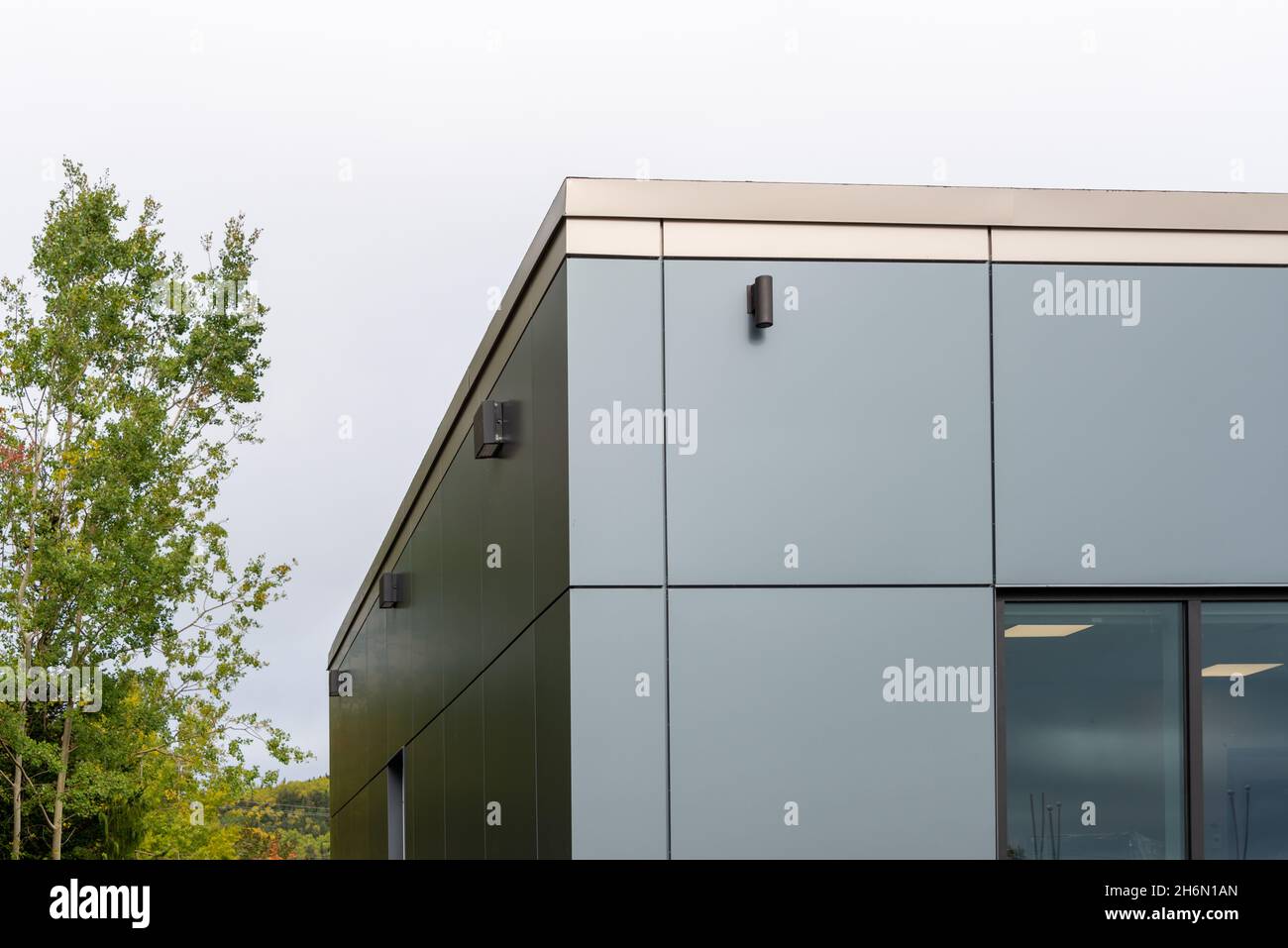 La parete esterna di un edificio contemporaneo di stile commerciale con pannelli compositi in alluminio e finestre in vetro. L'edificio futuristico Foto Stock