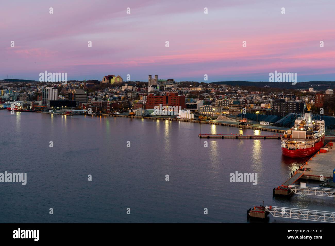 Un cielo rosa serale che si affaccia sul Porto di St. John con la nave della Guardia Costiera Canadese, Louis St Laurent, e le navi di rifornimento di petrolio e gas ormeggiate. Foto Stock