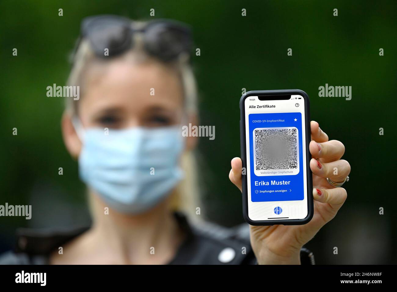 Symbol foto vaccinazioni privilegi, donna mostra app CovPass su smartphone con certificato di vaccinazione digitale europeo, incluso il codice QR, Corona Foto Stock