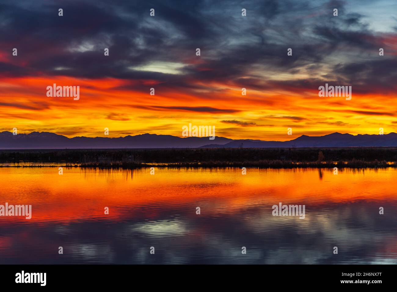 Il cielo si illumina quando il sole tramonta sull'acqua a Farmington Bay Waterfowl Manage Area, Farmington, Davis County, Utah, USA. Foto Stock