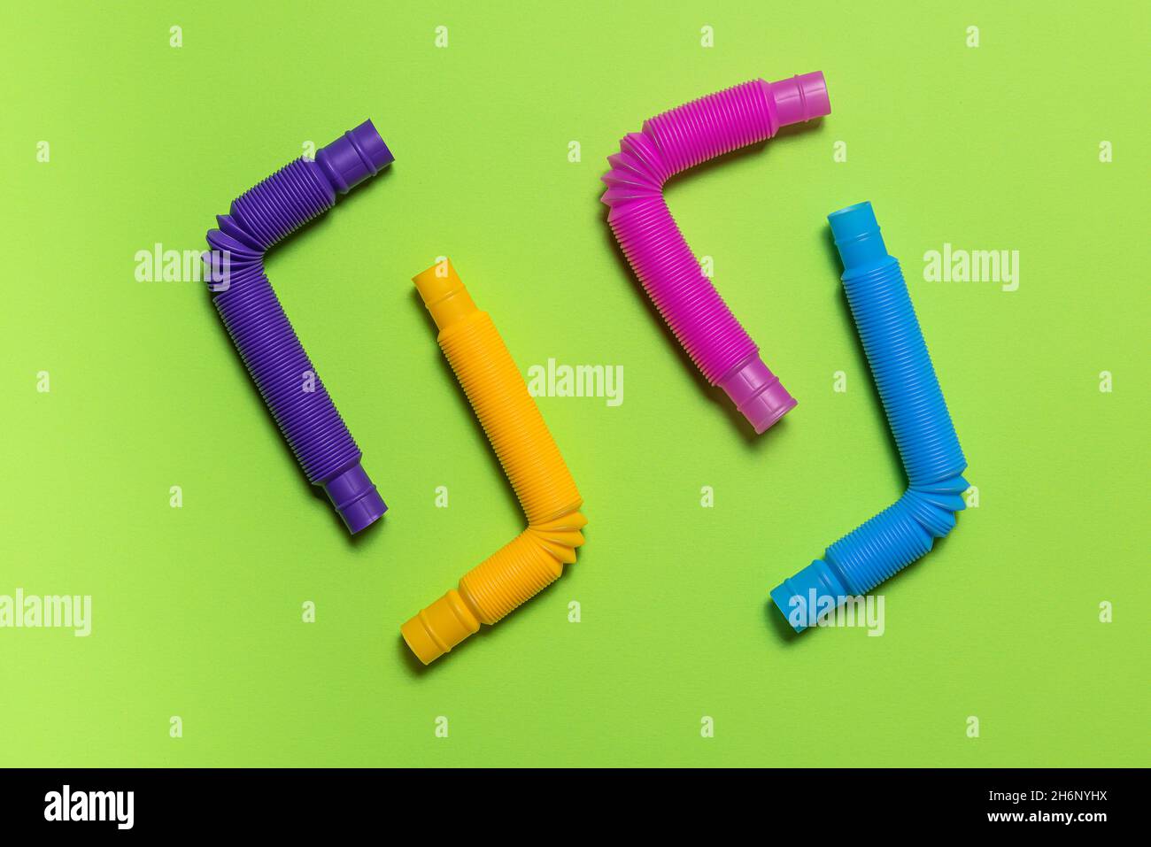 Quattro colorati giocattoli per bambini con tubo pop blu, rosa, viola e giallo piegati ad angolo retto. Set di allegro plastica antistress multicolore tubi su Foto Stock