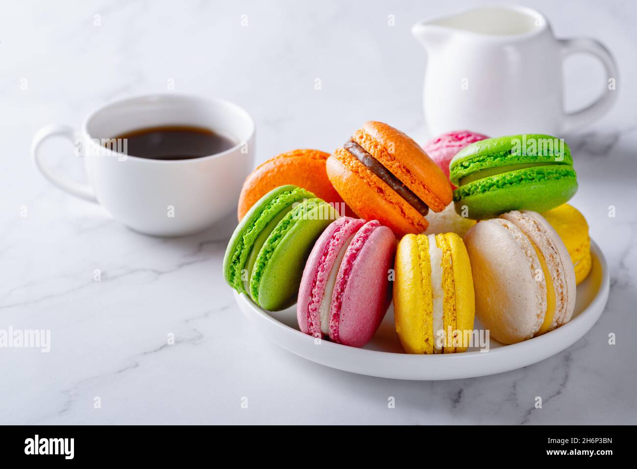 Dolci macaron francesi e caffè su tavola bianca Foto Stock