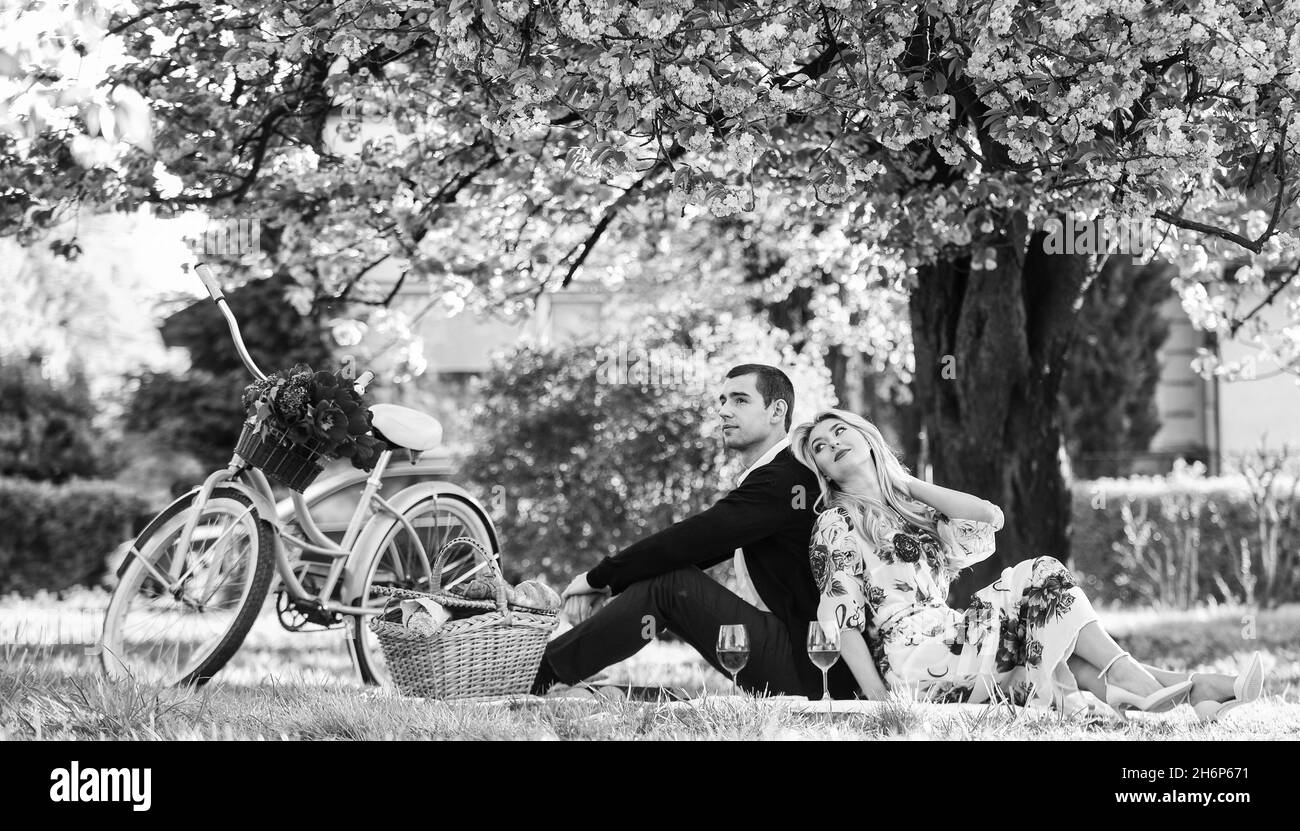 Fine settimana di primavera. Romantico pic-nic con vino. Dia spontaneamente i regali unici e rari. Coppia felice amorevole rilassarsi nel parco con cibo. Godendo loro Foto Stock