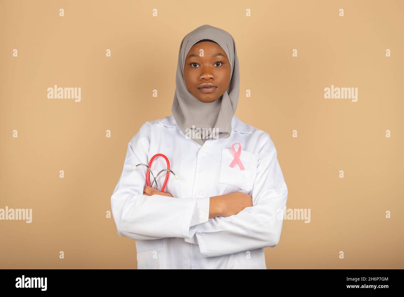 Assistenza sanitaria per le donne musulmane. Ritratto di una dottore afro-americano che indossa una bandana e cappotto bianco che posa con le braccia incrociate. Foto Stock