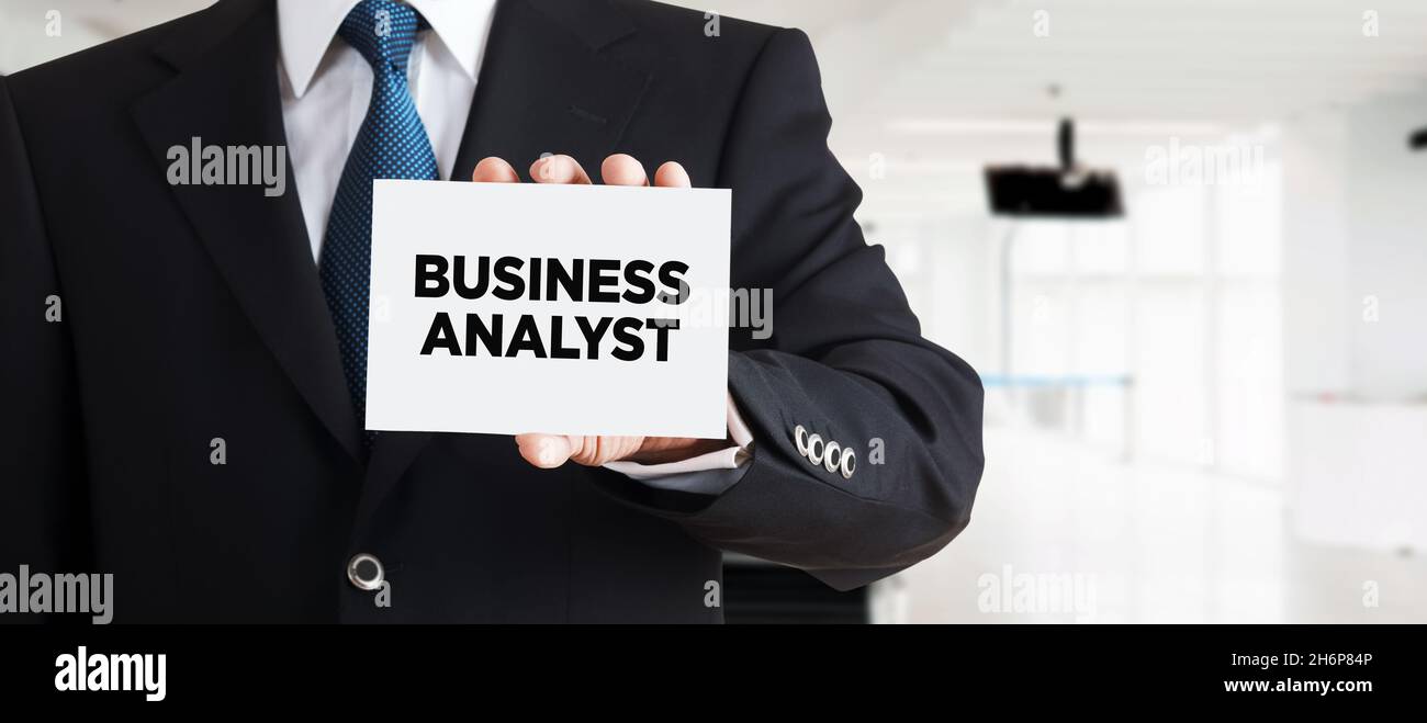 Businessman mostra un biglietto da visita con la parola business analyst. Concetto di finanza aziendale. Foto Stock