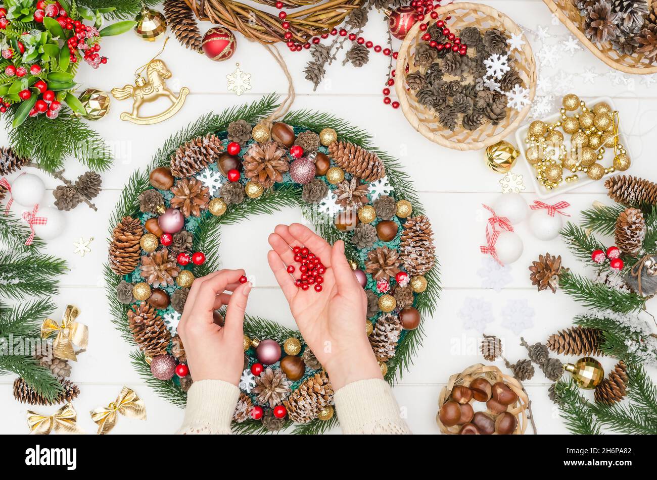 Facendo un grande wreath di Natale passo per passo, punto 17 - prenda e colla le piccole sfere rosse sulla colla calda Foto Stock