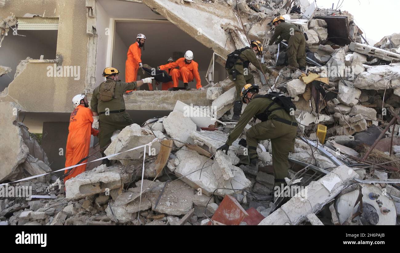 I soldati israeliani dell'unità di salvataggio del comando Home Front e i membri della squadra di identificazione delle vittime di calamità Zaka camminano attraverso le macerie di un edificio collassato mentre prendono parte a un'esercitazione di ricerca e salvataggio in un grande sito di demolizione il 16 novembre 2021 a Tel Aviv, Israele. Il trapano Home Front simula l'operazione di ricerca e salvataggio preparando scenari che potrebbero distruggere edifici e intrappolare i cittadini a causa di un terremoto importante o massicce barrature di razzi. Foto Stock