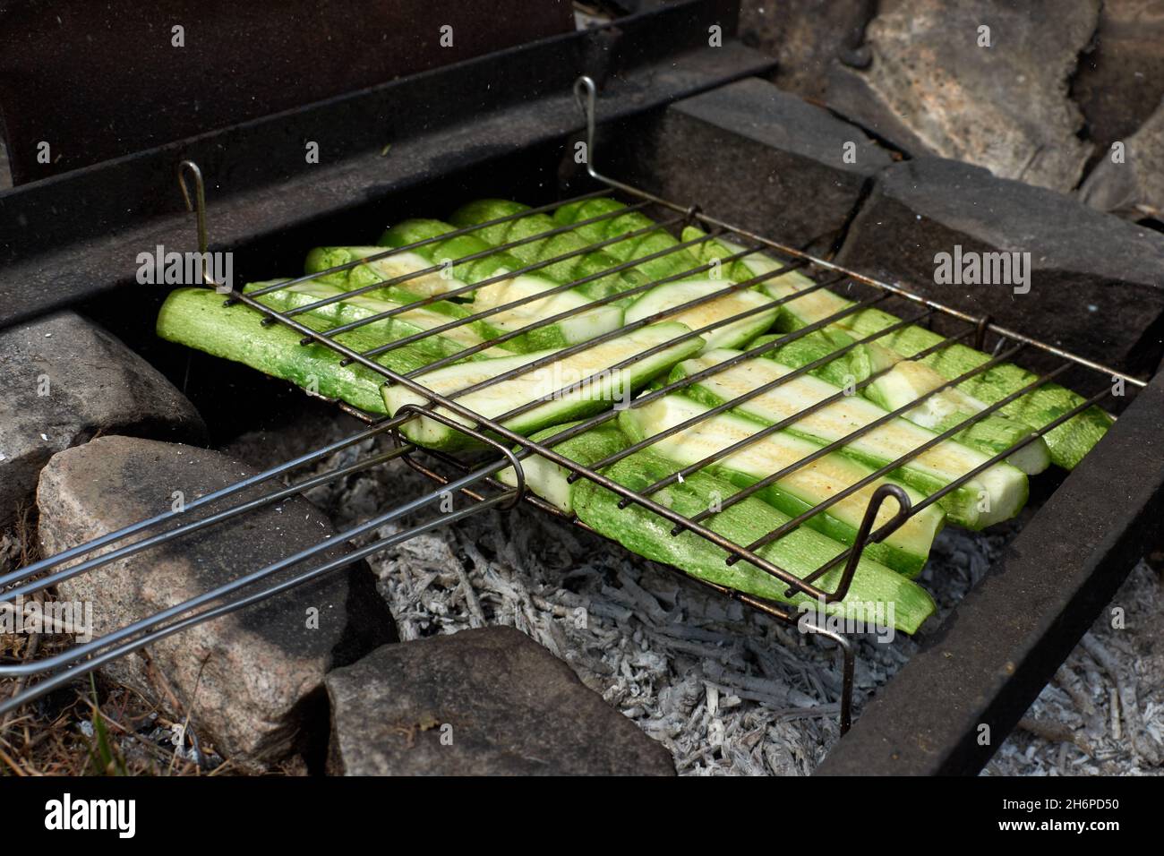 Grigliare zucchine su barbecue con fiamme e fumo. Messa a fuoco selettiva. Cibo estivo. Idee per barbecue, grigliate, barbecue. Foto Stock